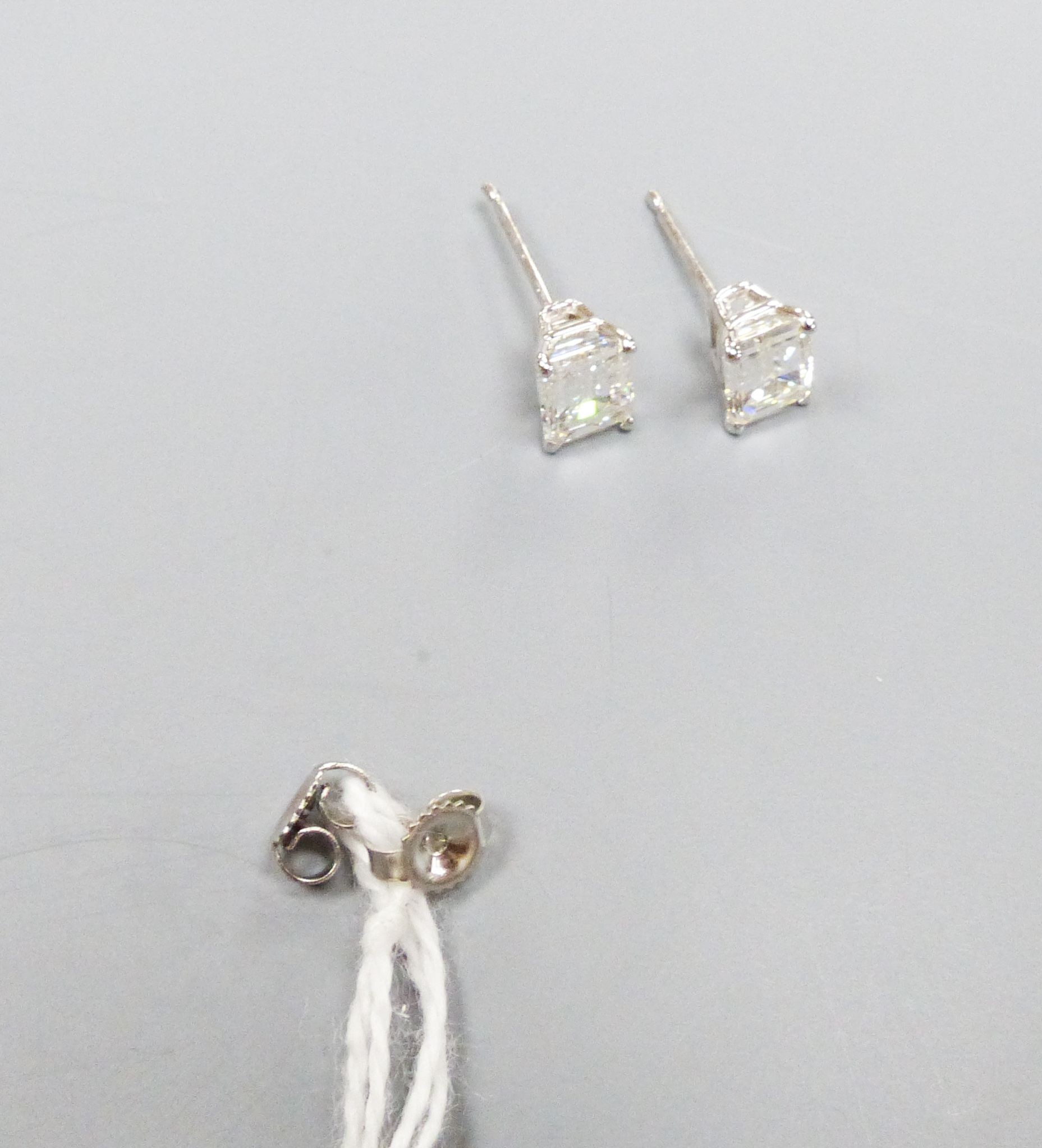 A modern pair of white metal and solitaire emerald cut diamond set ear studs, gross weight 1.1 grams